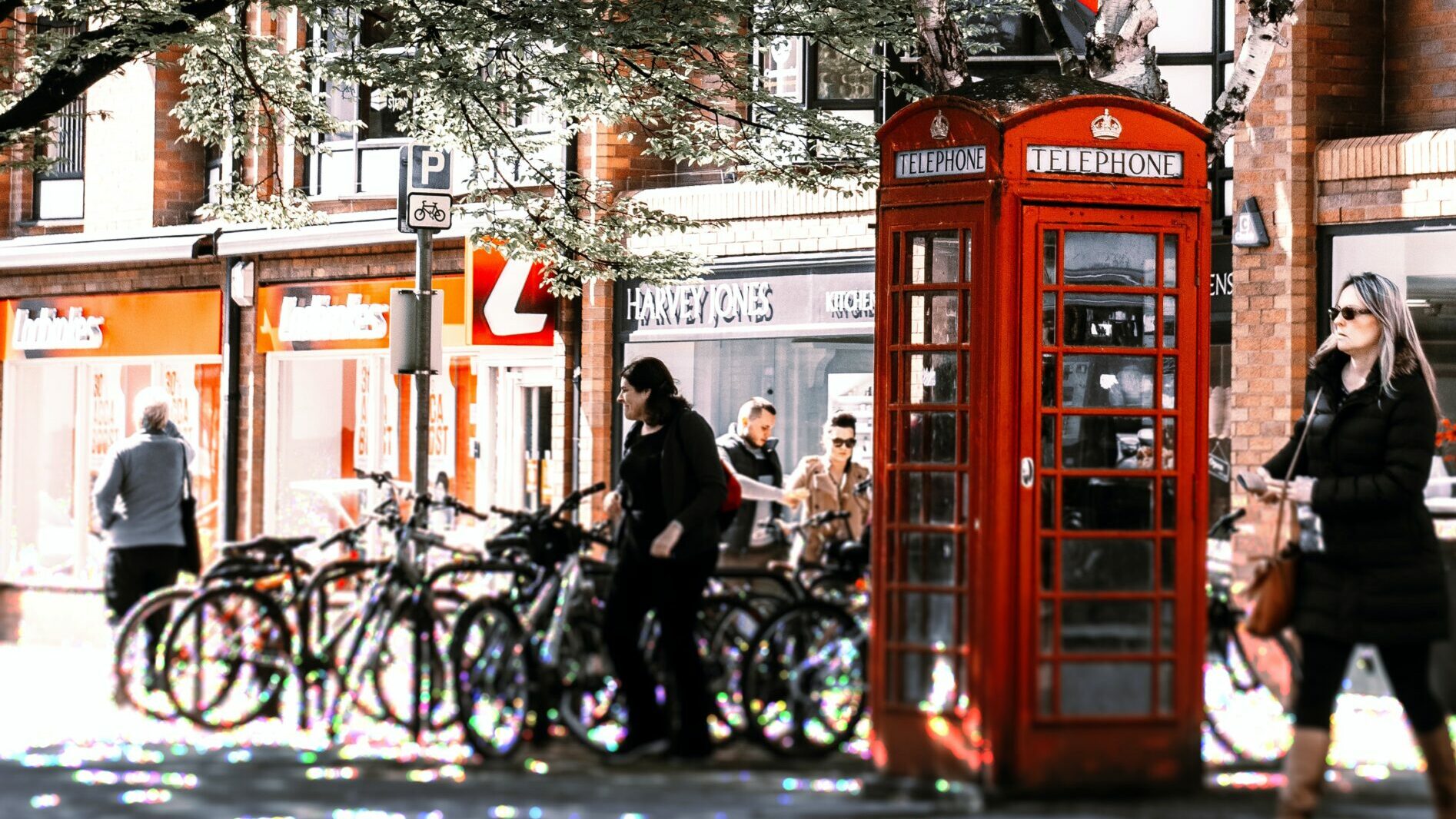 Red telephone box in town with people walking
